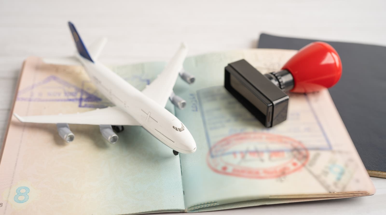 Toy airplane on an open passport with a visa stamp and a red rubber stamp, symbolizing international travel and visa approval.